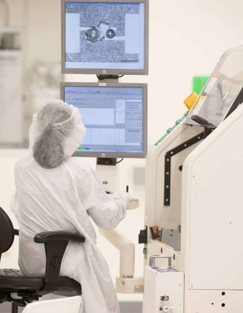 Female manufacturer works on two computers in a science lab